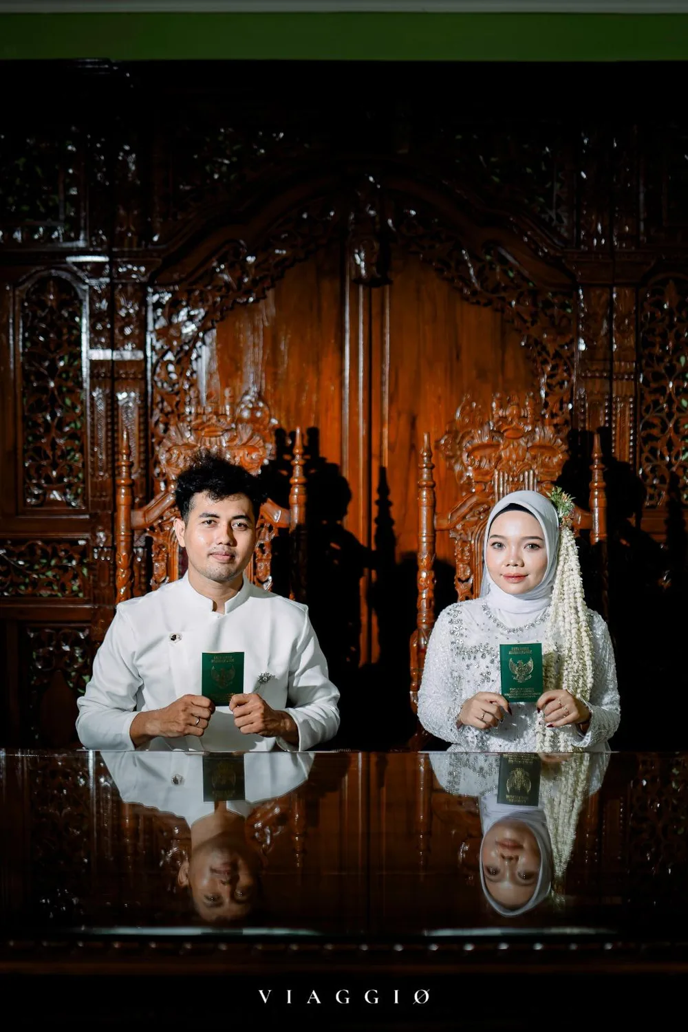 Pasangan duduk menunjukkan buku nikah