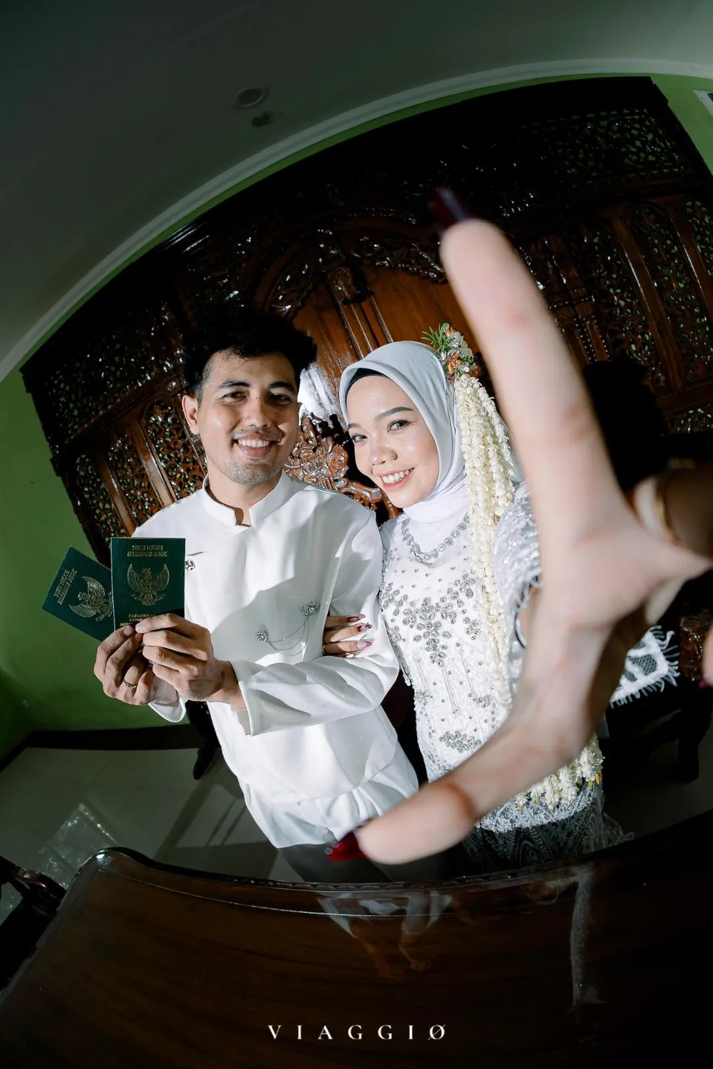 Selfie playful pasangan dengan buku nikah