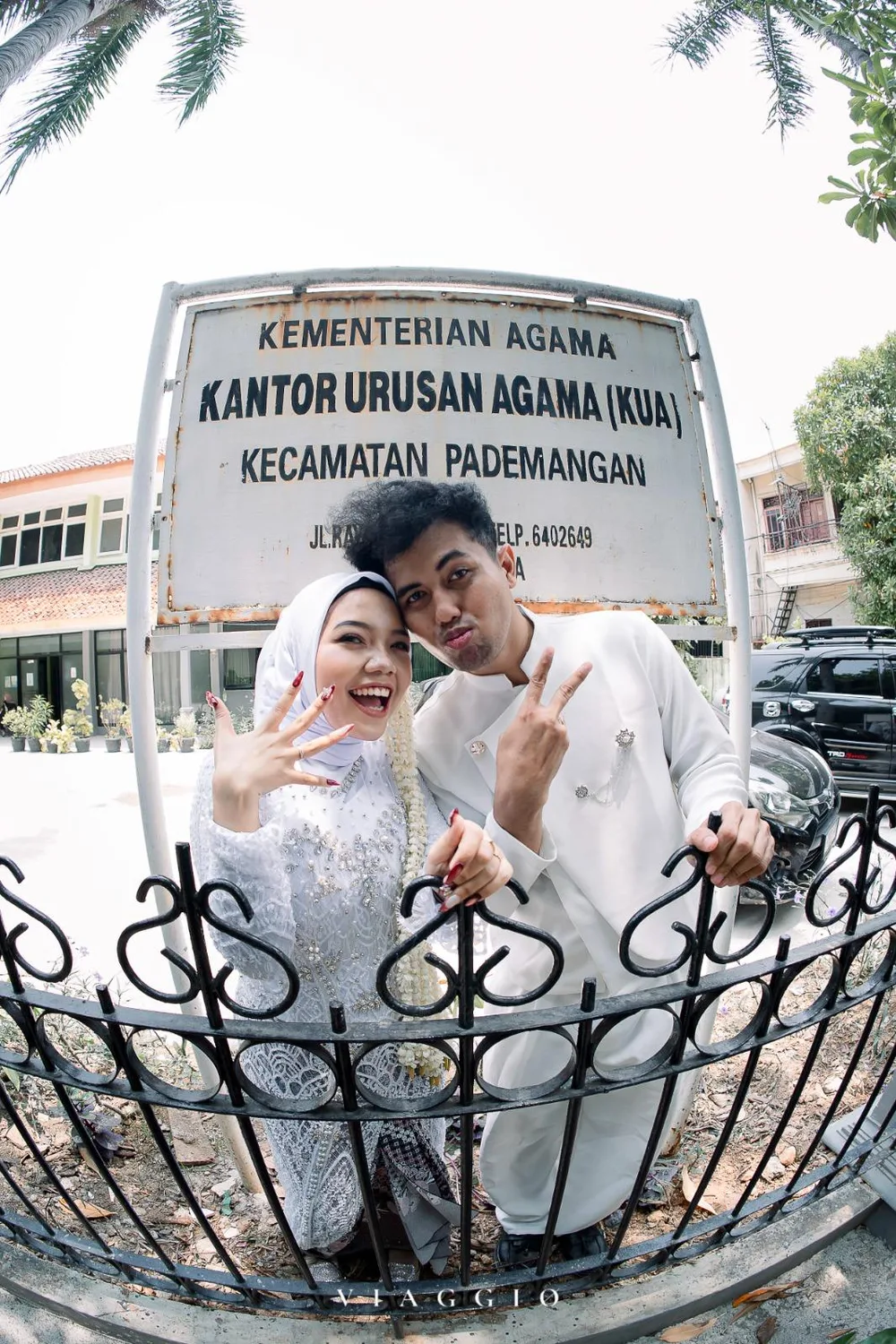 Pasangan playful di depan papan KUA Pademangan