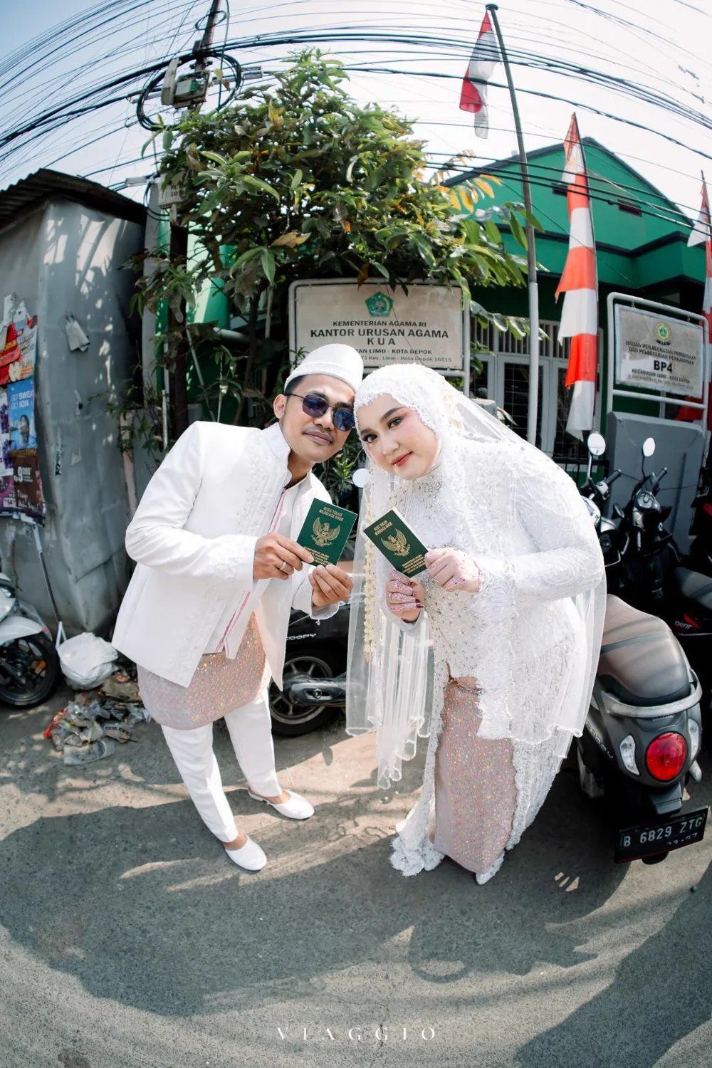 Pasangan playful dengan buku nikah di depan KUA Limo