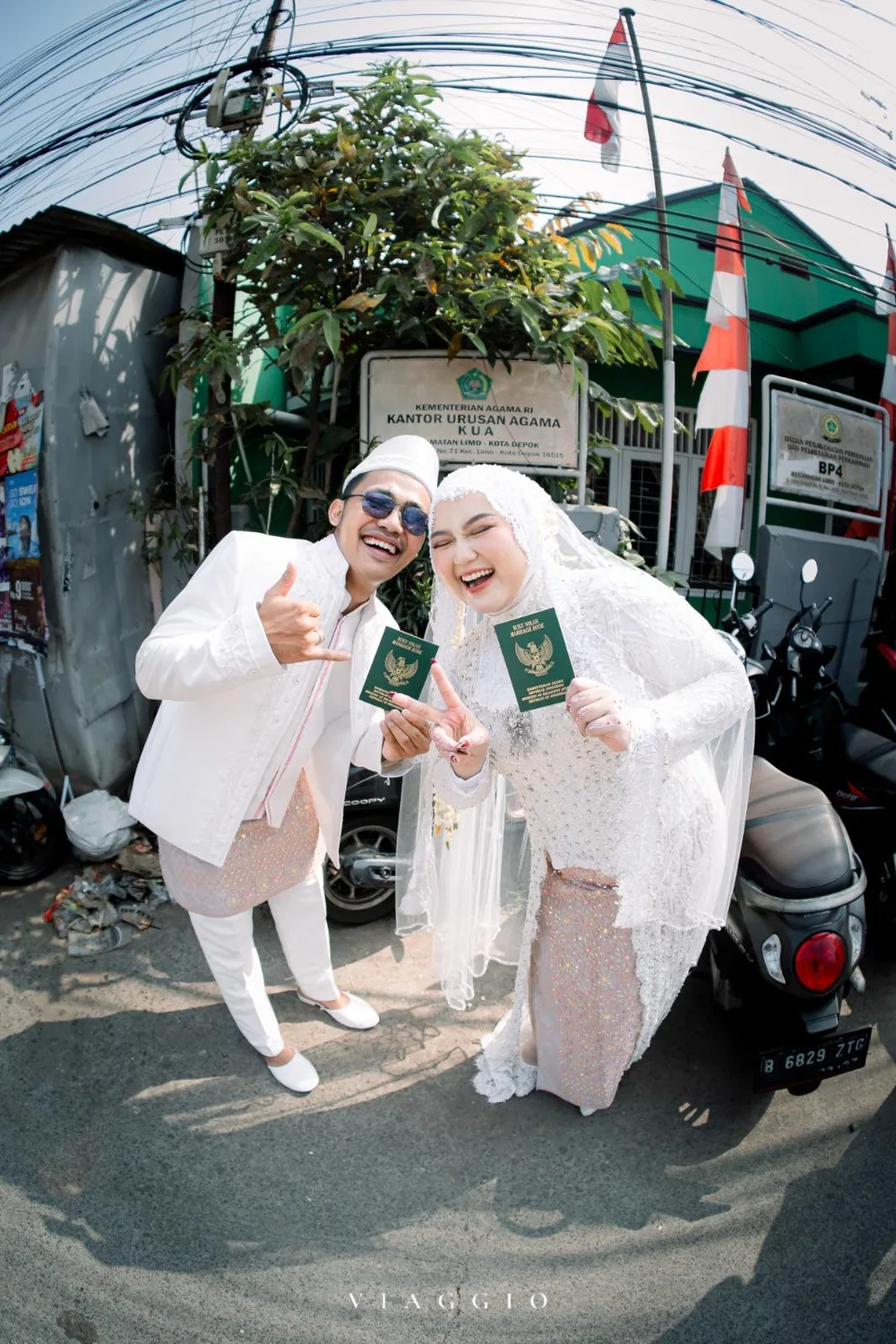 Pasangan tertawa lepas dengan buku nikah di depan KUA Limo